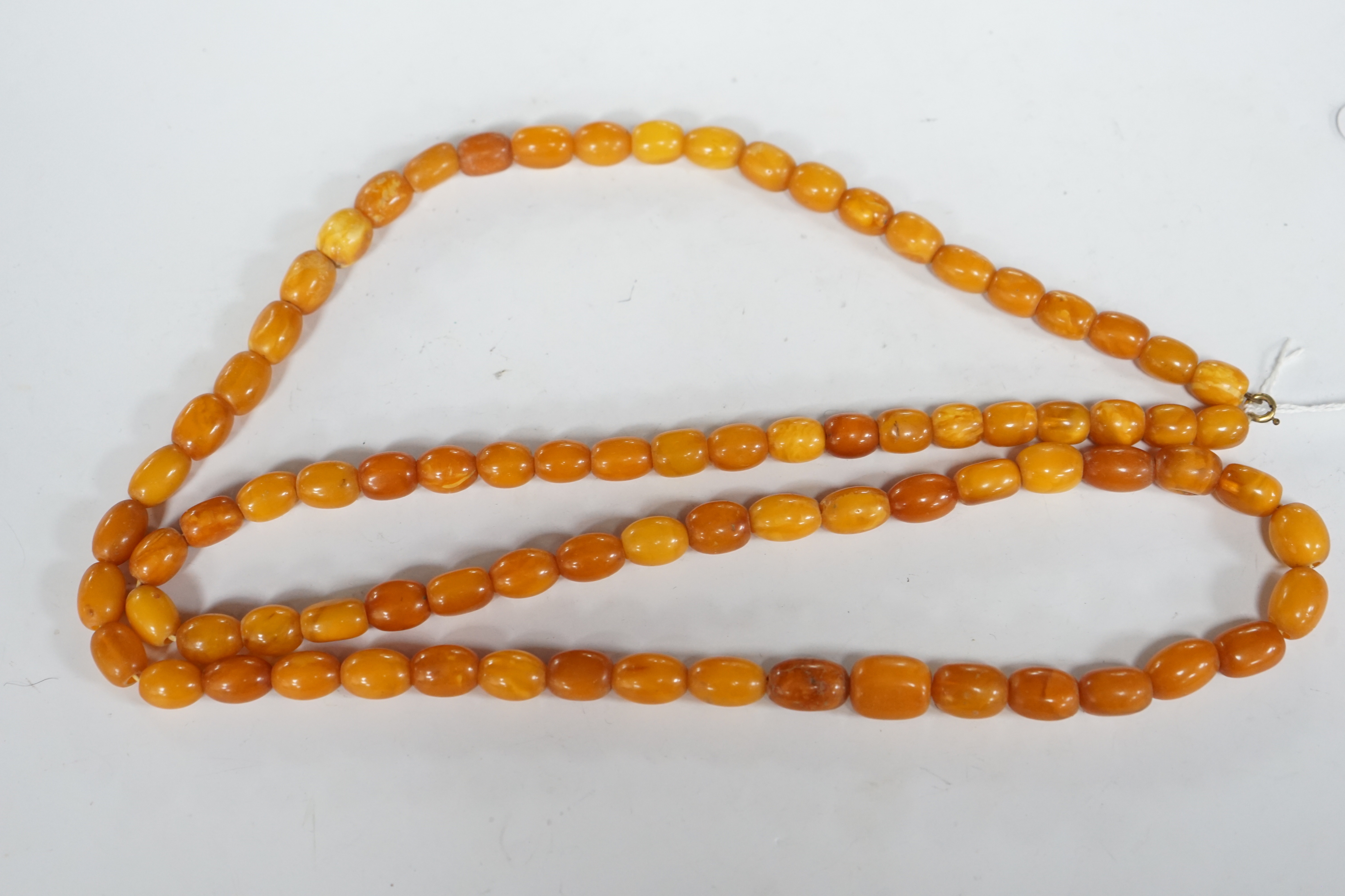 A single strand, barrel and oval amber bead necklace, 108cm, gross weight 76 grams.